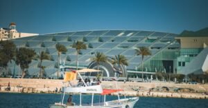 A leisure boat sailing by the Bibliotheca Alexandrina with a backdrop of palm trees, showcasing Alexandria's vibrant seascape.